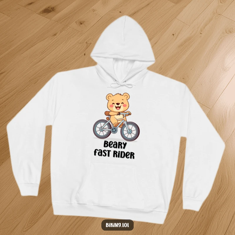 Funny hoodie showing a happy bear cub with a wide smile, pedaling a bicycle featuring exaggeratedly large wheels.