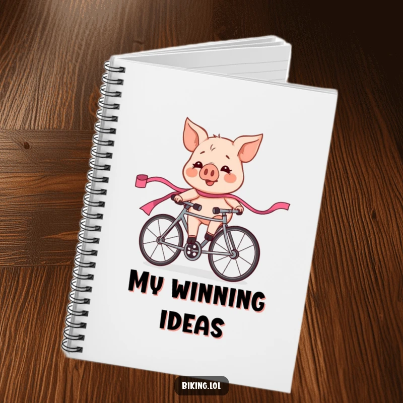 Funny pig character in a bicycle race, looking flushed and exhilarated, trailing a pink ribbon, on the cover of a humorous notebook.